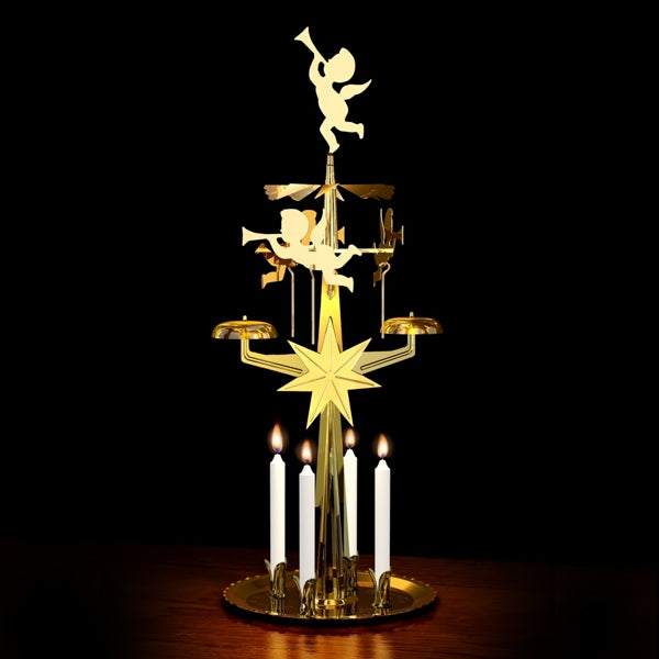 brass cherub angel chimes with lit candles against a black background