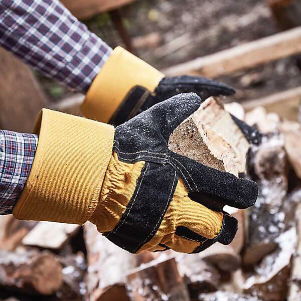 Person wearing Briers Thermal Tuff Rigger gloves while handling firewood, showing leather palm and knuckle protection in use