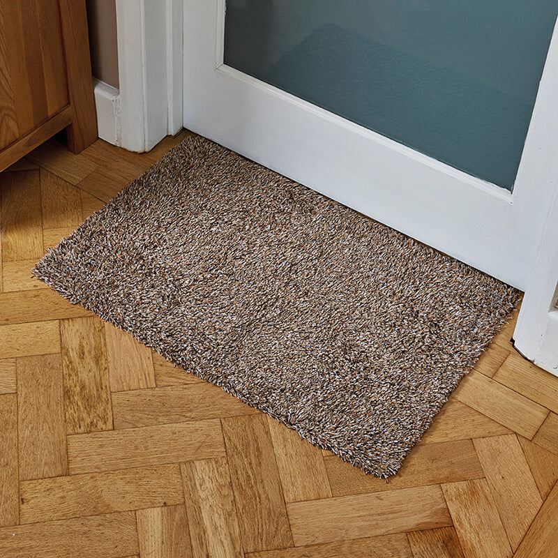 Oatmeal Ulti-Mat washable indoor doormat by a front door on a herringbone wood floor