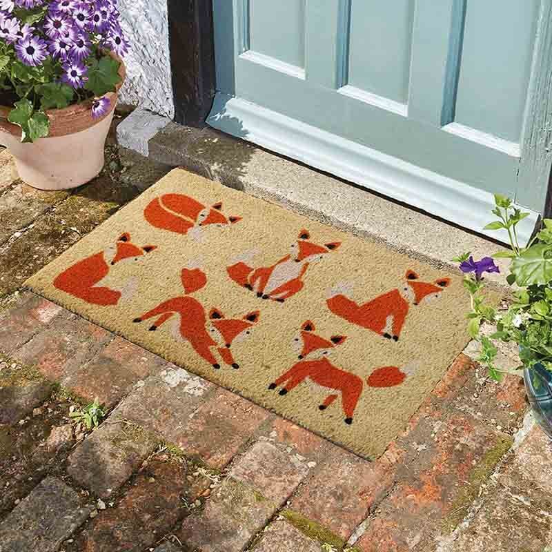 Six vixens fox coir doormat with six foxes in playful poses on a brick step by a front door