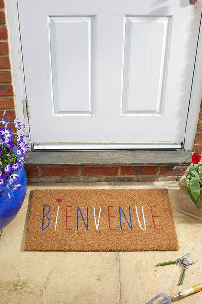 Bienvenue French welcome coir doormat with blue, white and red lettering on a stone step by a front door