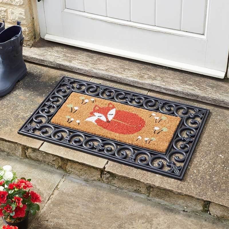 Fox Hollow coir doormat insert with fox design in rubber frame outside a front door, with wellington boots and potted flowers