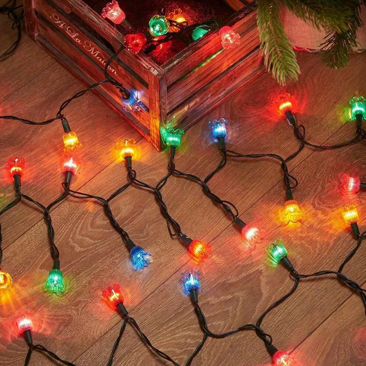 NOMA multicolour canterbury belles LED string lights laid out on a wooden floor