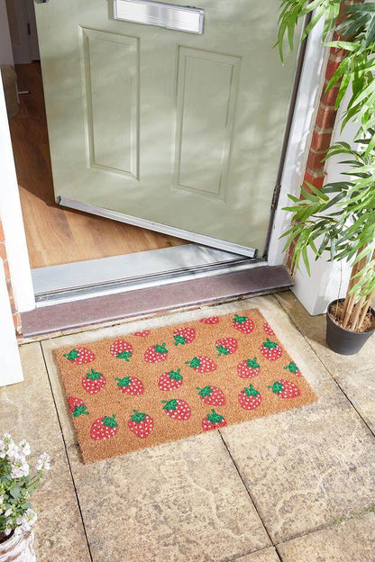 Strawbs coir doormat with strawberry print on a stone step by a front door