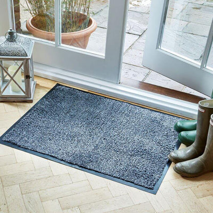 Framed anthracite Ulti-Mat washable indoor doormat on a wood floor by a patio door, with wellington boots
